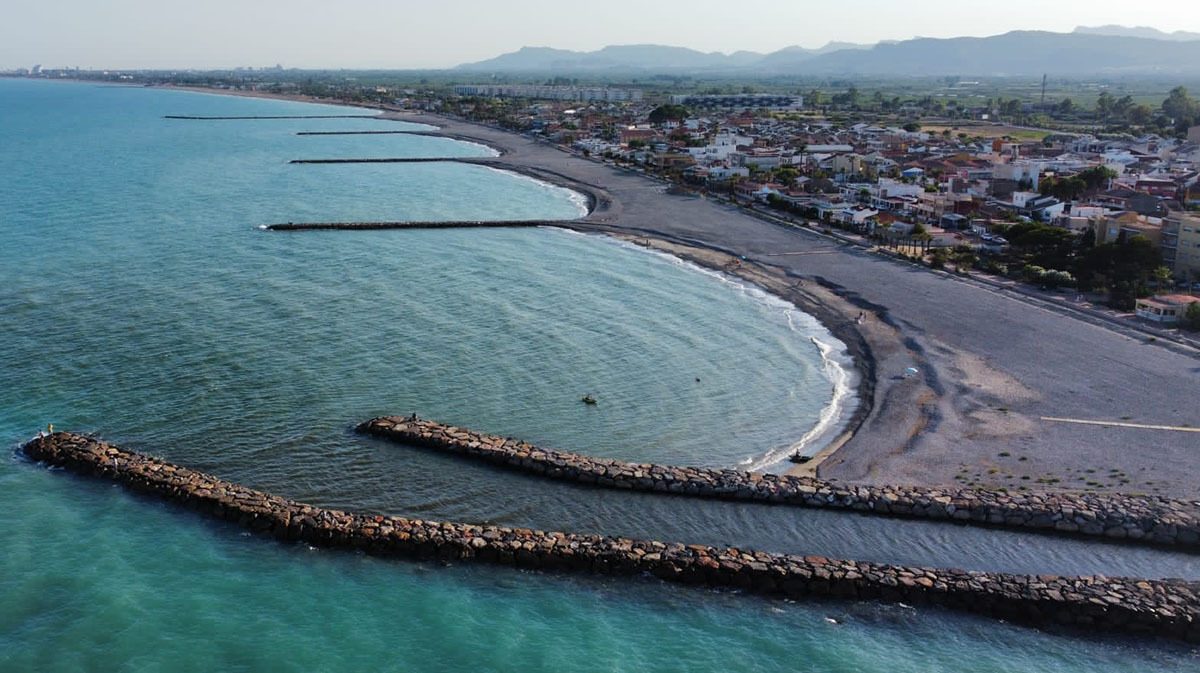 Vista aèria de les escolleres de la platja d'Almenara amb el poble al fons